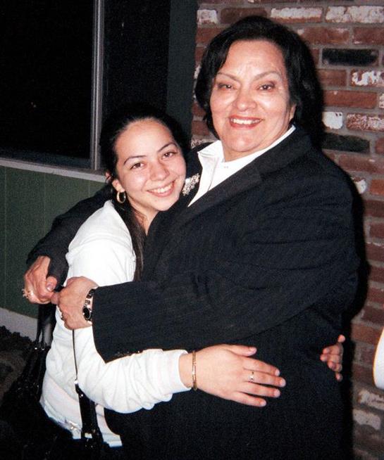 Smiling women share a joyful hug during a friendly gathering in a cozy indoor environment.