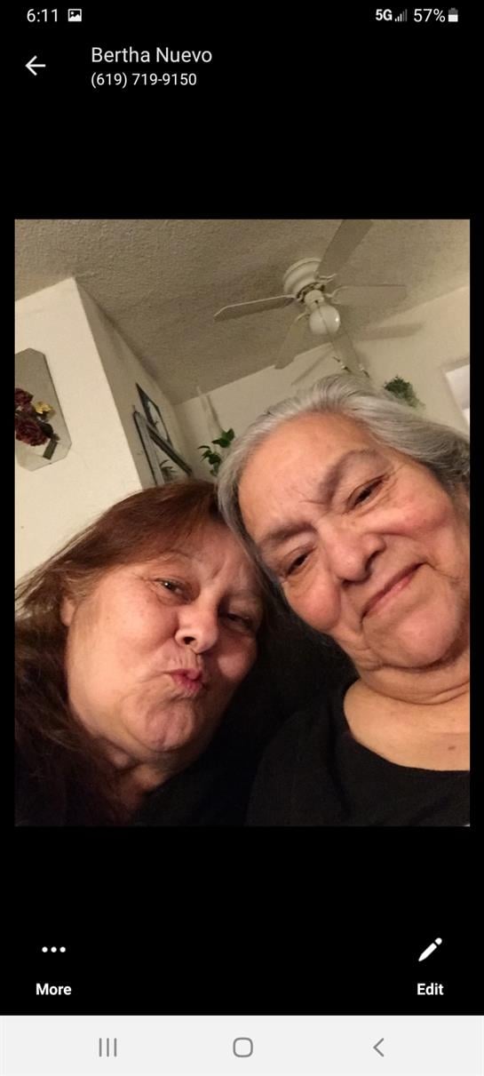 Two women pose closely for a selfie, sharing smiles and a warm moment in a cozy environment.