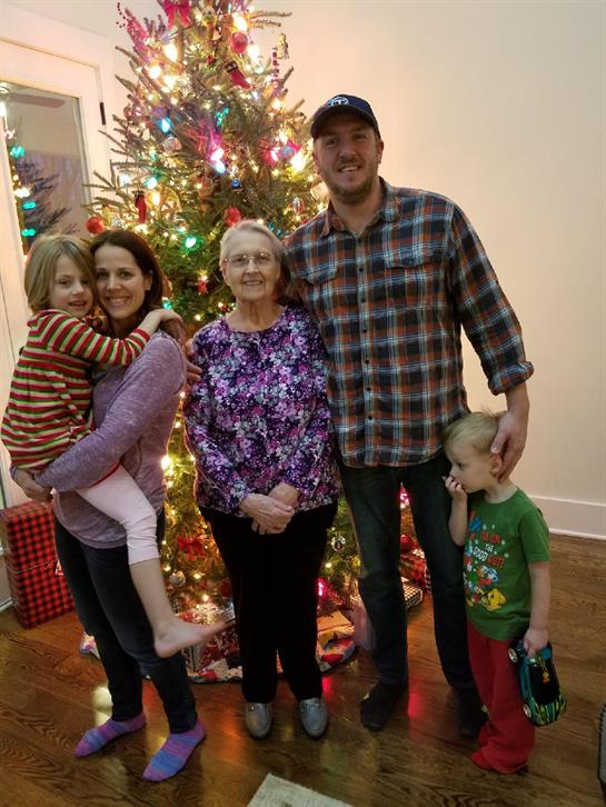 Family is gathering together for Christmas in a cozy, festive living room with a Christmas tree.