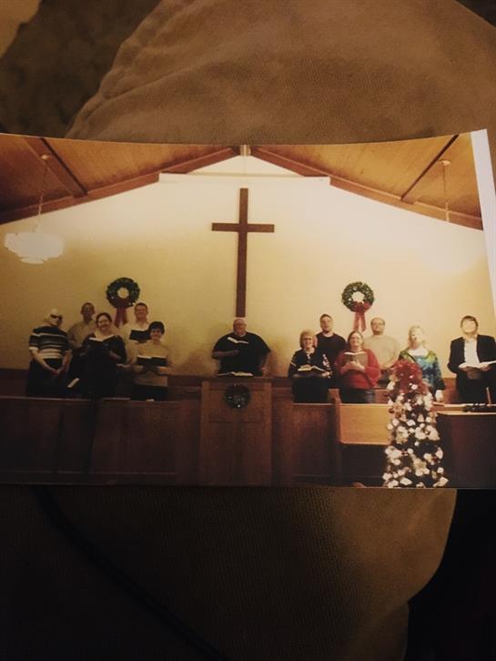 Choir members sing joyfully in a decorated church during a Christmas service.