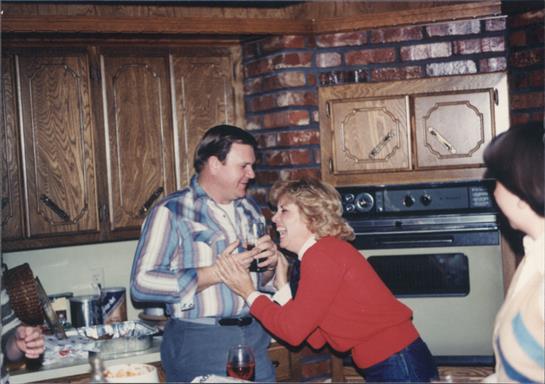 Two people engage in a lively and playful conversation while surrounded by food in a kitchen.