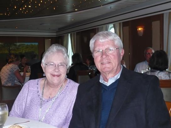 Happy couple seated at a dining table, enjoying a meal together in a warm atmosphere.
