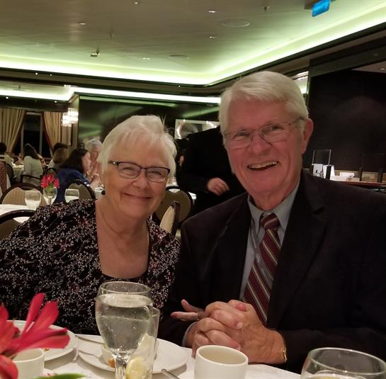 A happy couple shares a joyful moment during a dinner event in a restaurant setting.