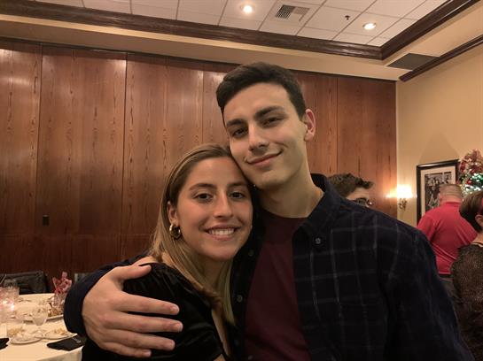 Two young adults share a happy moment together at a celebration in a cozy indoor venue.
