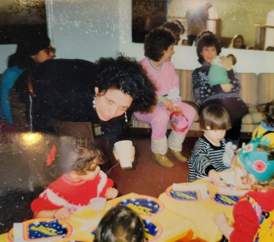 Kids and adults gather together, sharing laughter and snacks in a warm, inviting environment.