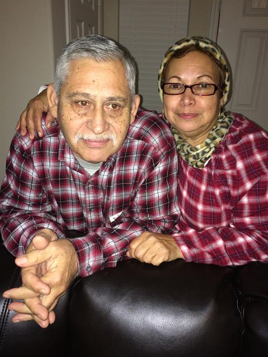 Two adults share a warm moment together while dressed in matching checkered outfits at home.