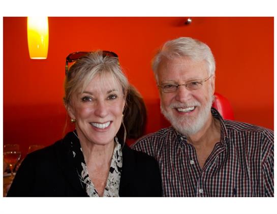 Two people enjoy a joyful moment together, smiling warmly in a lively and colorful cafe environment.