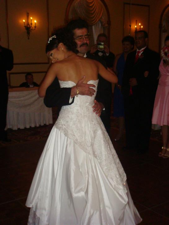 A couple dances close during their wedding reception, surrounded by joyful guests and decorations.