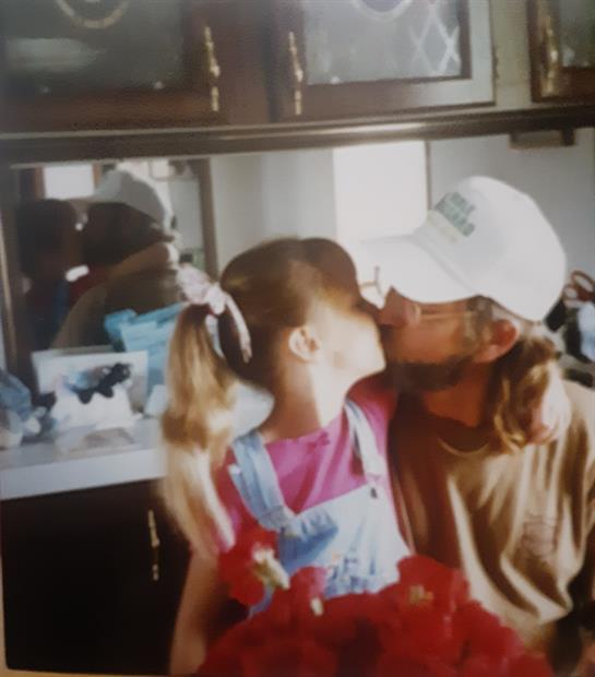 A father and daughter share a sweet moment in their home kitchen, embracing affection and joy.