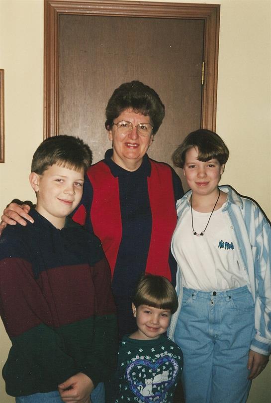 A woman poses with four children in a warm indoor environment showcasing joy and family connection.