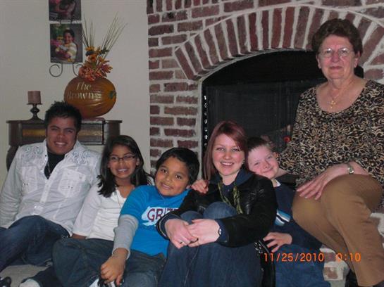 Six family members enjoy quality time together by a warm fireplace on a chilly evening.