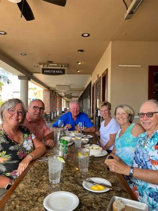 A group of friends gathered around a table sharing food and laughter in a relaxed outdoor setting.