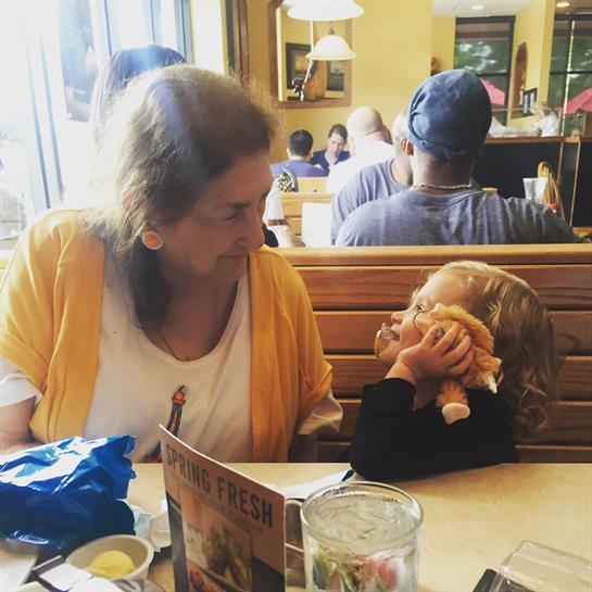 Grandmother and granddaughter share a joyful interaction at a bustling restaurant during lunchtime.