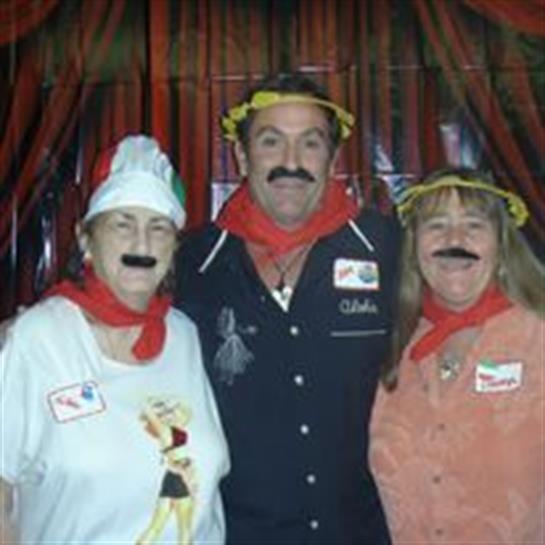 Three friends dressed in colorful costumes with fake mustaches enjoy a lively party atmosphere.