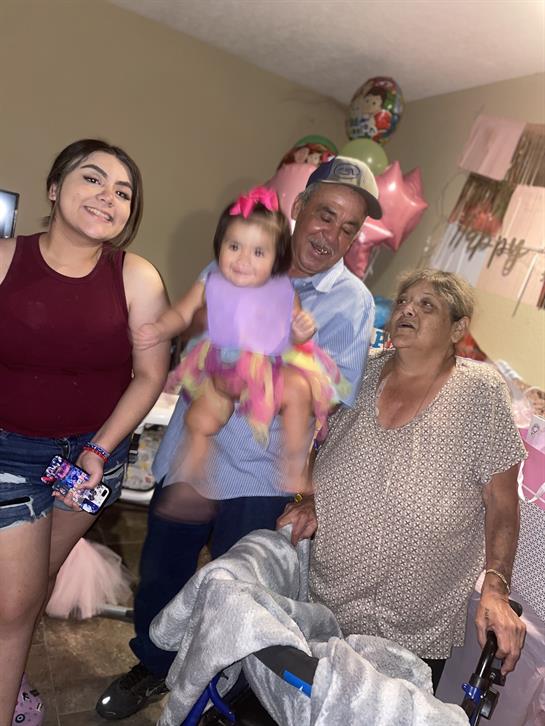 Four family members smile in a cozy room, celebrating joyfully with decorations around.