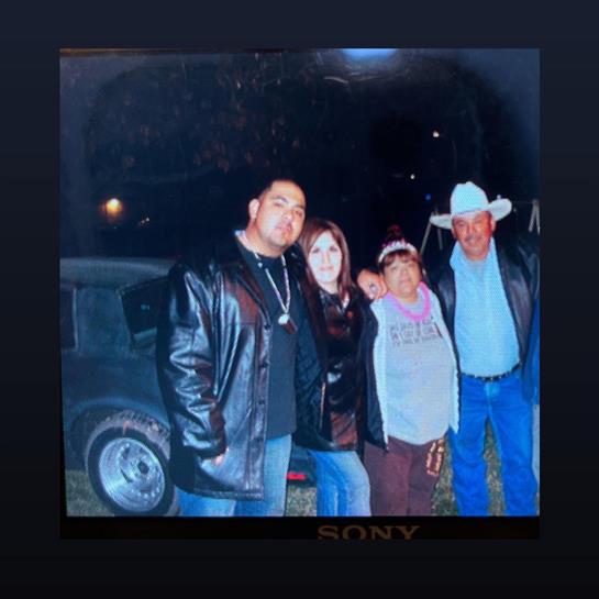 Four friends stand together near a vehicle, enjoying a night out under the stars.