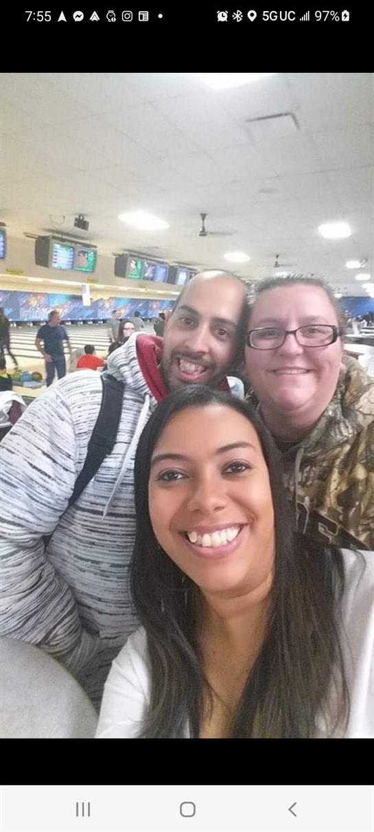 Three friends gather for a cheerful selfie while enjoying a lively bowling session.