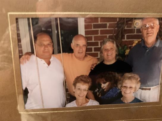 Family members are gathered together, smiling and enjoying each other's company inside a cozy home.