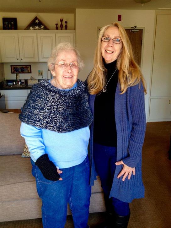 Two women share a joyful moment together in a living room, showcasing warmth and connection.