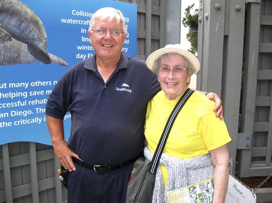 Happy couple poses for a picture outside a marine conservation center on a sunny day.