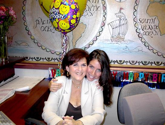 Women enjoy a joyful birthday celebration in a vibrant office setting filled with decorations.
