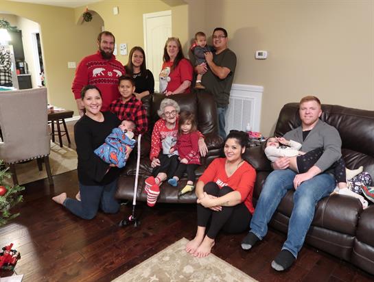 Family members gather in a warm atmosphere, celebrating together with children in festive attire.