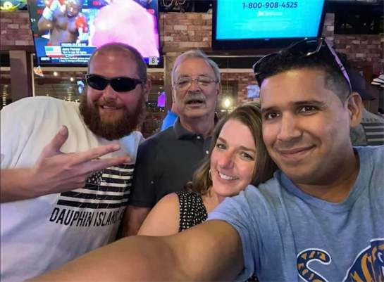 Friends posing for a selfie at a bustling bar, enjoying drinks and a lively atmosphere.