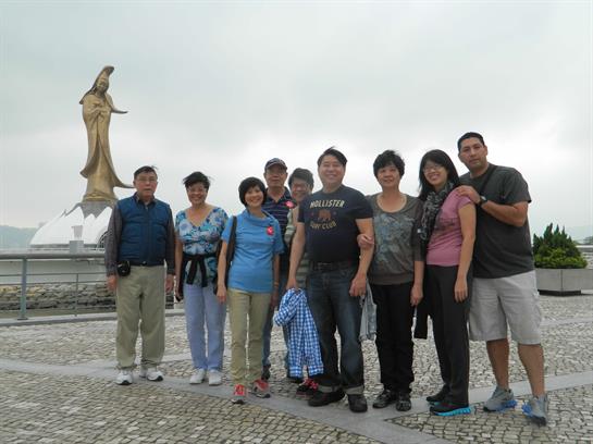 A group of friends poses for a fun photo beside a large statue on an overcast day.
