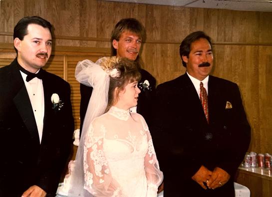 A smiling bride and groom celebrate with friends in formal attire at their heartfelt wedding.