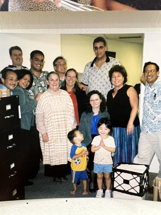 A gathering of people in a bright office, sharing smiles and joy together, showcasing camaraderie.