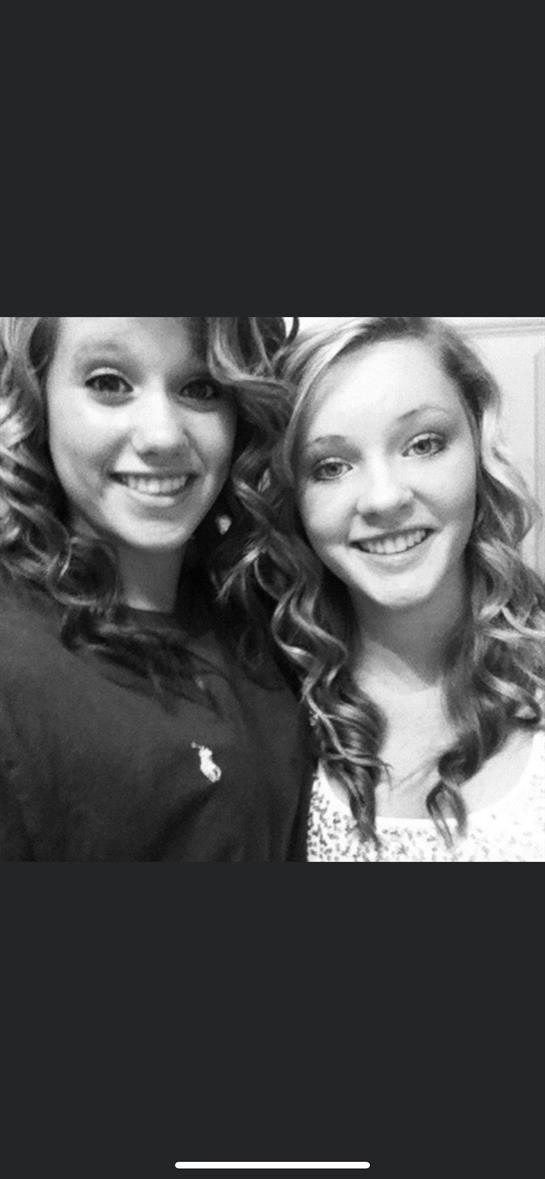 Two friends pose closely, smiling and displaying their curly hair in a relaxed atmosphere.