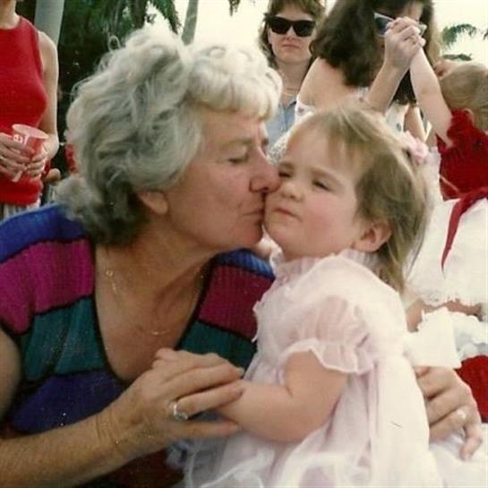 A loving kiss exchanged between a grandmother and her granddaughter at a joyful family gathering.