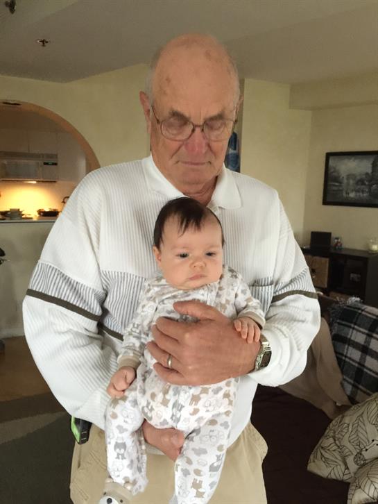 An elderly man lovingly cradles a baby, showcasing a moment of family bonding and warmth.