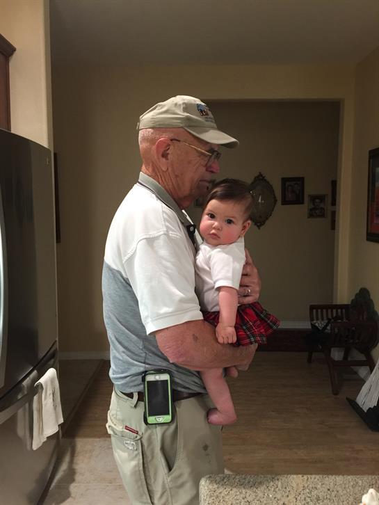 A loving grandfather cradles his adorable grandchild in a warm living room setting.