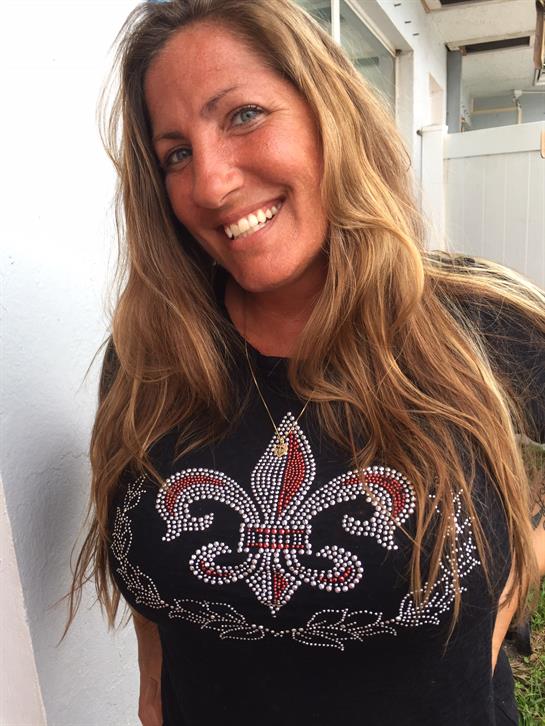Woman displays a joyful expression, wearing a black shirt adorned with a sparkling design.