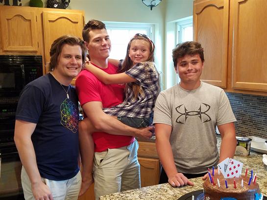Friends enjoy a joyful moment in a kitchen while posing for a group photo with a child.