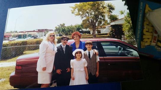Group of five people dressed in formal clothes enjoying a family moment outside a house.