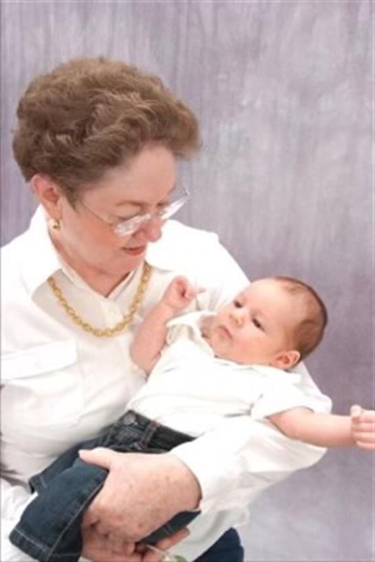 A grandmother smiles while cradling her grandchild, creating a moment of tenderness.