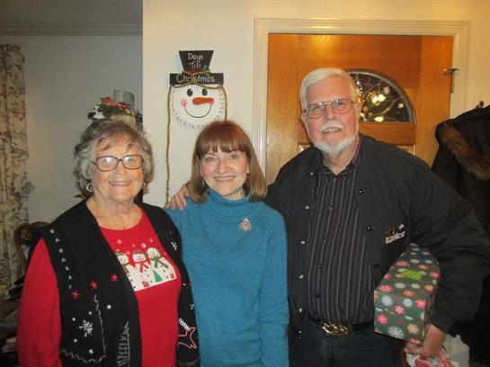 Three family members pose together with holiday decorations, sharing festive joy in a cozy setting.