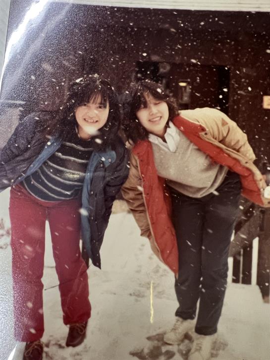 Two friends pose playfully in a snowy setting, their faces bright with happiness and laughter.
