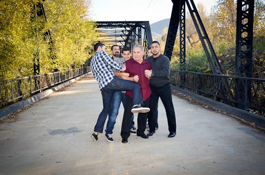 A group of five friends joyfully interacts on a bridge surrounded by colorful autumn trees.