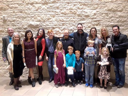 Adults and kids gather, smiling at the camera in a stylish venue for a special occasion.