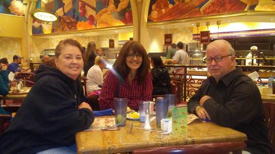 Friends sit around a table in a colorful restaurant, sharing laughter and food during lunch.