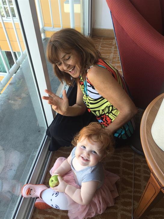 A woman and a joyful child share a playful moment by a sunlit window.