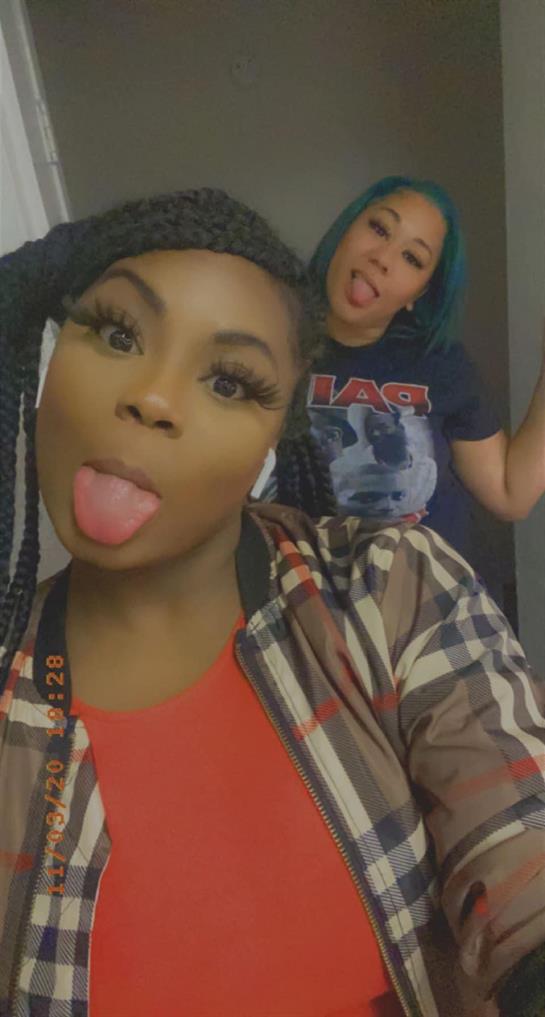 Two friends share a lighthearted moment at home, sticking out their tongues and smiling.