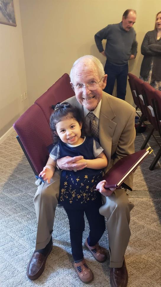 Grandfather and granddaughter smile together during a family event, creating cherished memories.