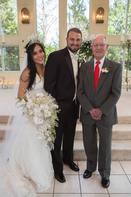 A joyful moment captured at a wedding, featuring the bride, groom, and grandfather together.