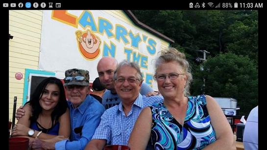 Friends smile and pose together at a lively outdoor event beside Larry's on the lake.