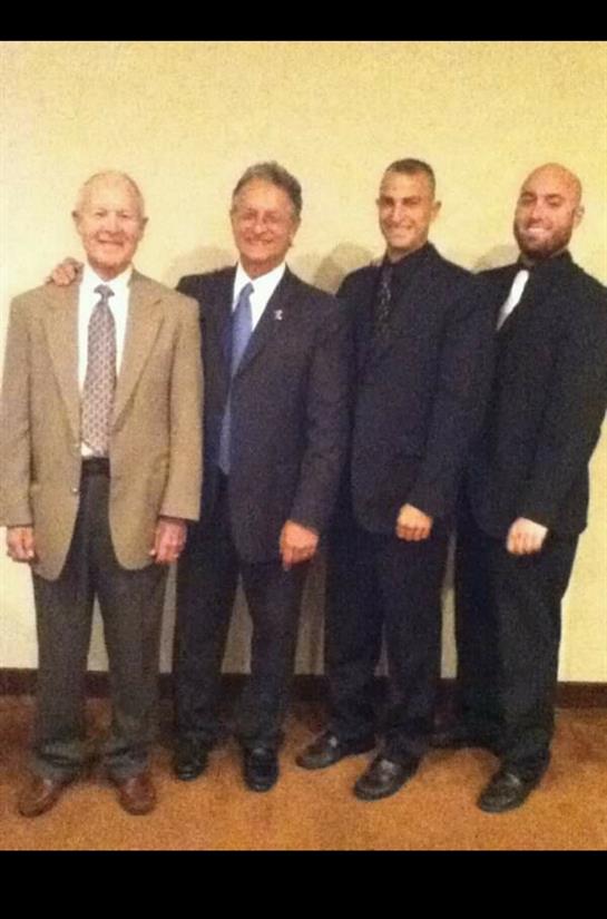Four men in suits pose together, showcasing family unity and style in a cozy environment.