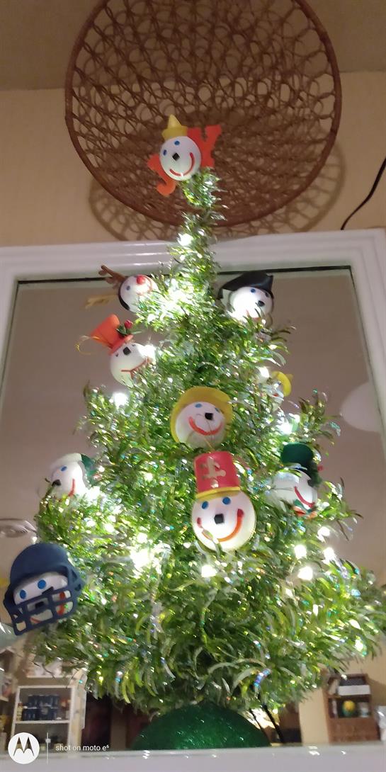 A vibrant tree adorned with smiling snowman ornaments lights up the cozy indoor space.